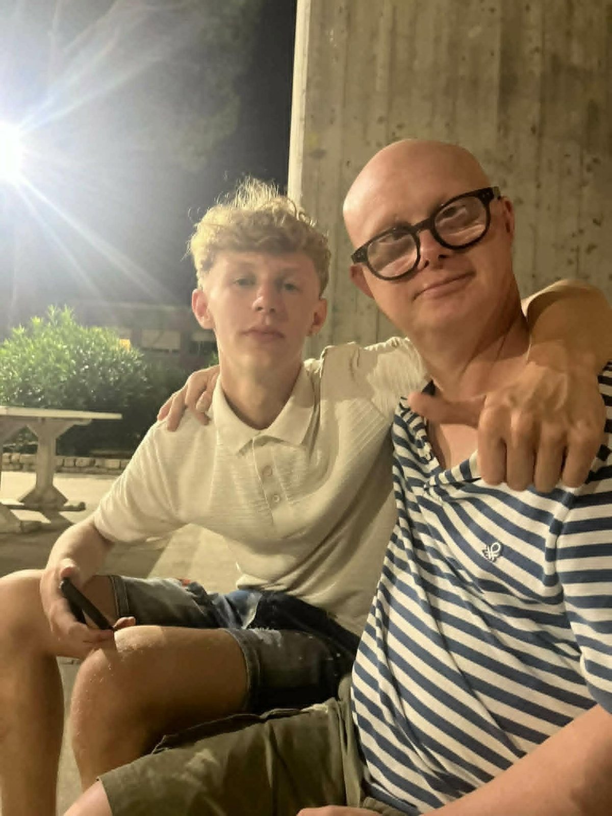 Due ragazzi abbracciati sorridono alla fotocamera in una serata estiva