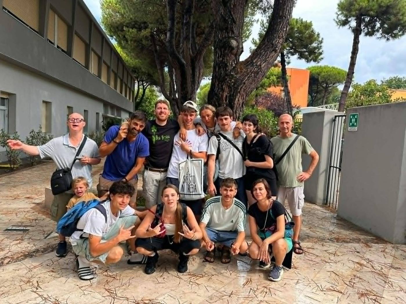 Il gruppo degli educatori volontari del campo estivo, in posa sotto i pini del villaggio