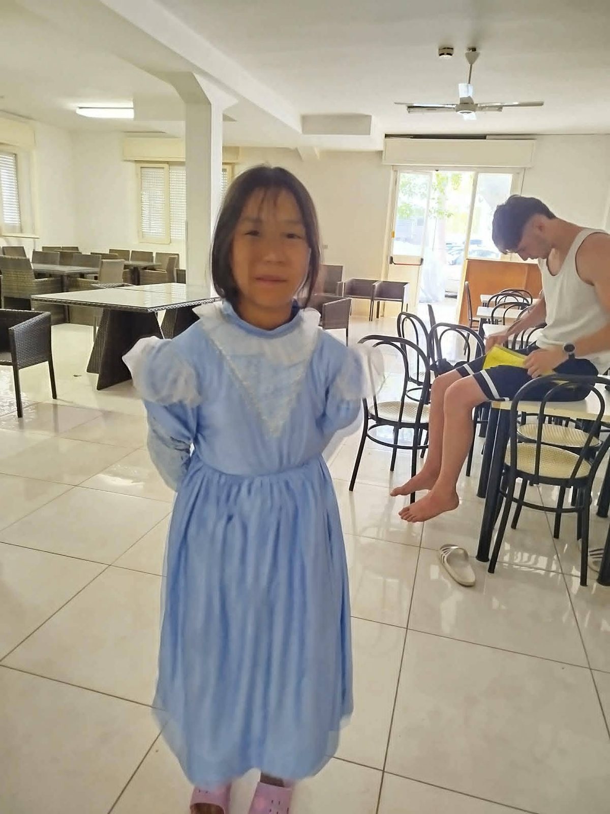 Una bambina in abito azzurro da principessa nella sala del villaggio