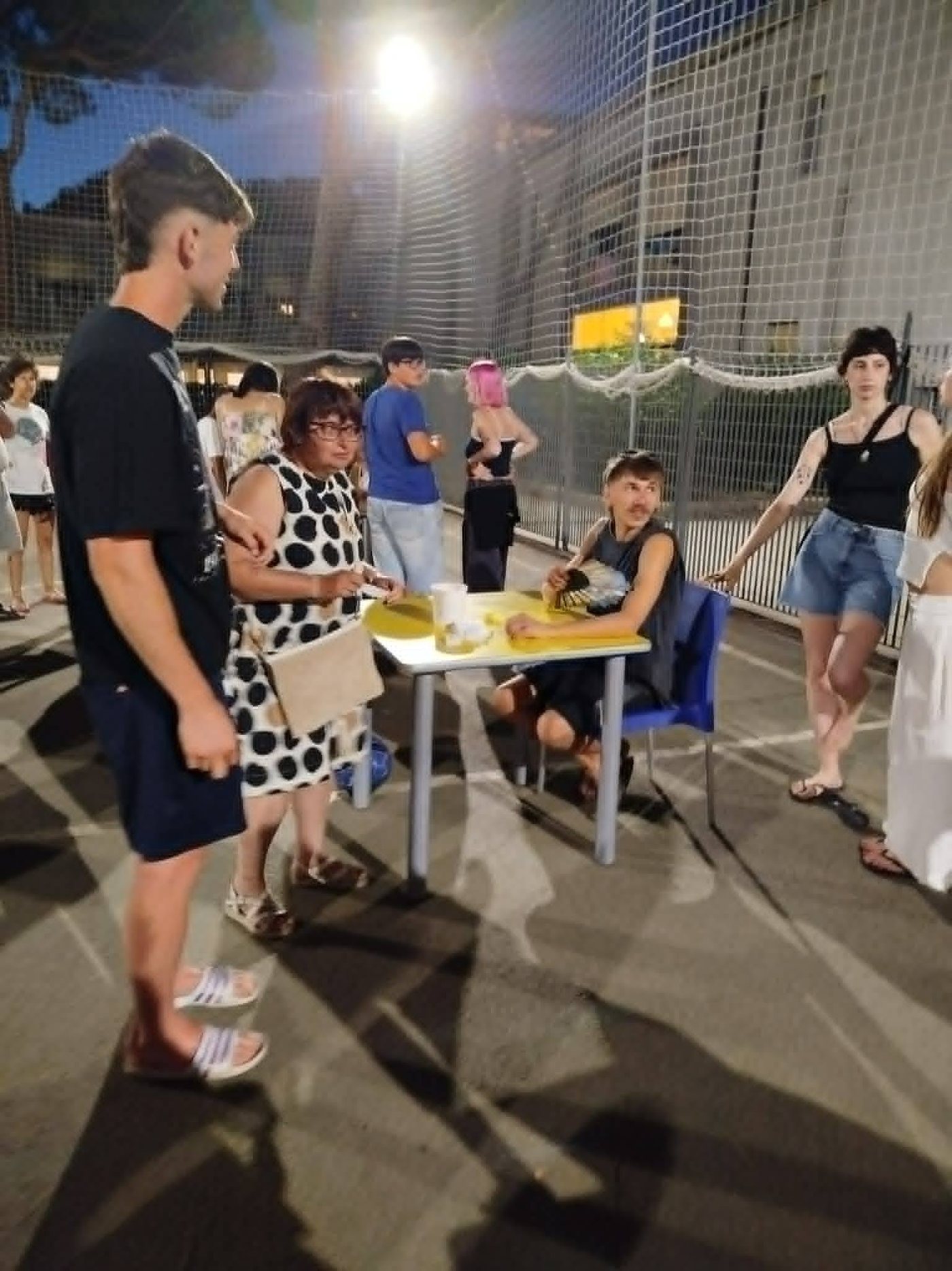 Una serata all'aperto: tavolini, chiacchiere e ragazzi in cortile