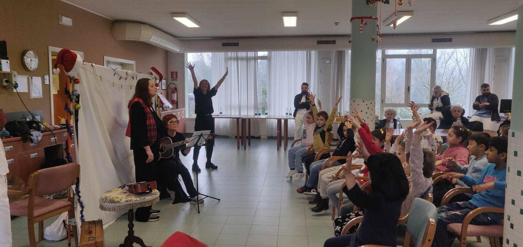 Deca, stariji i volonteri slušaju pozorišnu priču u domu za stare